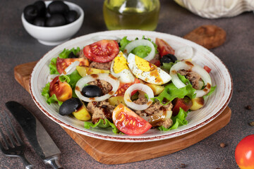 French salad Nicoise with tuna, boiled potatoes, egg, black olives, tomatoes, onion and lettuce poured balsamic sauce, Close-up