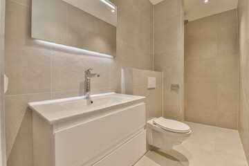 a bathroom with beige tile walls and white tiles on the wall, there is a toilet next to the sink