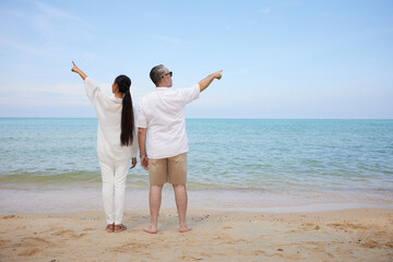 back couple pointing and looking to sky on the sea