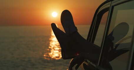 Feet, sunset and car at the beach with freedom, happy driver and shoes out window for travel, road trip and adventure break. Person, ocean drive and foot, sneakers or summer, vacation and relax