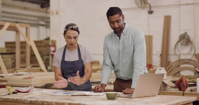 Carpenter, laptop and talking or planning in a workshop for manufacturing, wood and design process. A manager man and woman together for creative work, production and teamwork on carpentry project