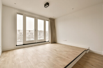 Obraz premium an empty room with white walls and wood flooring, looking out onto the balcony from the living room door