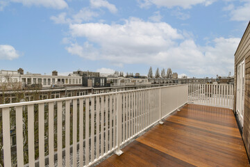 a balcony with wood flooring and white railings on the side of an apartment building looking out to the city
