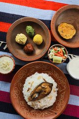 Khuder Bhat, Hilsa Khichuri Combo with salad, eggplant, borhani and Chui Pitha served in dish isolated on mat top view of indian and bangladeshi food