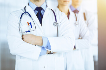 Group of modern doctors standing as a team with crossed arms and stethoscopes in a sunny hospital office. Physicians ready to examine and help patients. Medical help, insurance in health care, best de