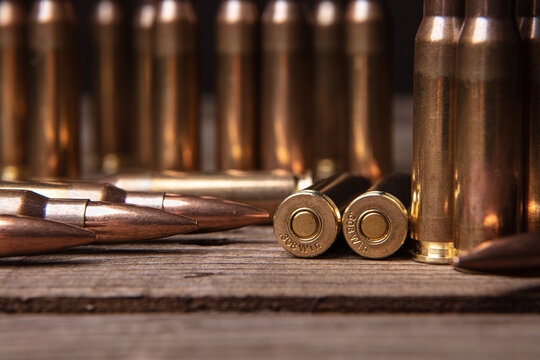 Close-up of .308 caliber rifle cartridges. Ammunition for weapons on a wooden surface. Dark back.