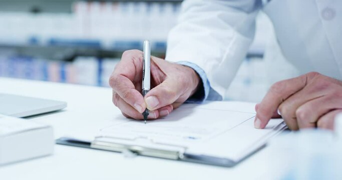 Hands, pharmacy and man writing a prescription for medicine on a counter for healthcare and wellness. A male medical worker or pharmacist doctor with a pen and paper for pharmaceutical notes