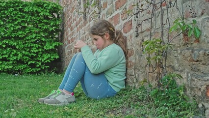 Upset Frustrated Depressed Young Caucasian Girl Sitting Alone Outdoors Against Brick Wall Hiding...