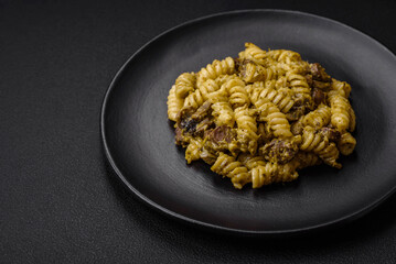 Delicious fusilli pasta with green pesto sauce, with salt and spices