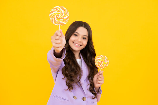 Teen girl hold lollipop caramel on yellow background, candy shop. Teenager with sweets suckers. Happy teenager, positive and smiling emotions of teen girl.