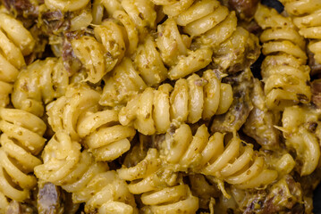 Delicious fusilli pasta with green pesto sauce, with salt and spices