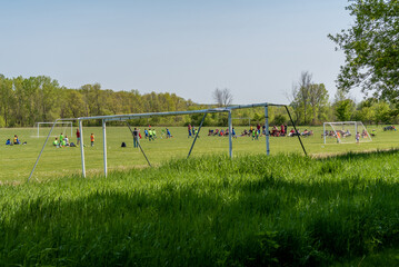 Obraz na płótnie Canvas People Watching A Youth Soccer Match In The Park In Spring