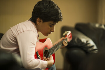 little boy playing red guitar