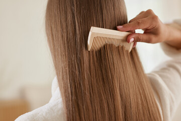 a young girl in a white coat takes care of her hair at home