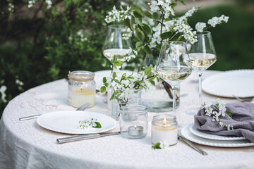 Rustic zero waste wedding decor with natural elements. Fresh spring blooming flowers, candles, linen napkins, wine glasses. Eco friendly decoration for the special holiday dinner. Romantic cozy place