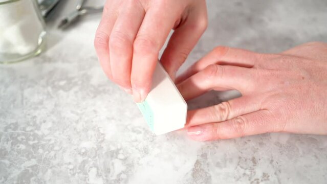 Woman finishing her manicure at home with simple manicure tools. Buffering nails with a nail buffer block.