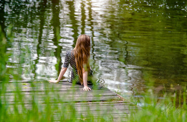 A girl stands on the shore of a lake
