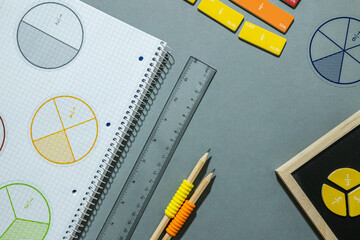 Fractions, rulers, pencils, notepad on gray background. Set of supplies for mathematics and for...