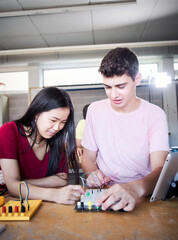 Vertical multiracial boy and girl students at technical high school look electronic board in...