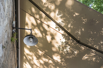 An exterior facade lamp under an extendable pergola