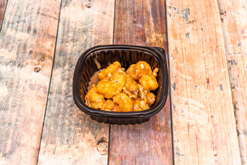 A black colored delivery container filled with some delicious dried fruit