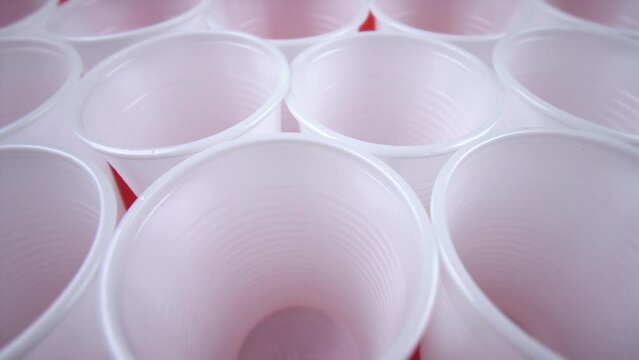 empty white disposable cups stand on red background closeup