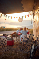 Couple having fun outdoors.Cheerful  man and woman Partying Near Modern Camper Van In Camping