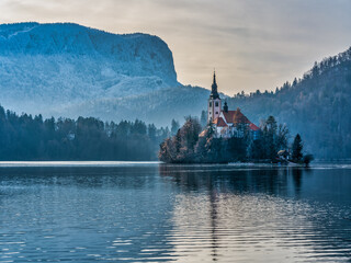 Close up shot of the island Church in the middle of lake bled and snow the mountain during winter, Slovenia