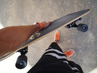 Point of view shot of skateboarder holding skateboard in hand with new smartwatch.