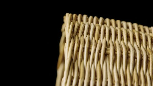 Fragment of a basket made of willow twigs or garden furniture. On black background