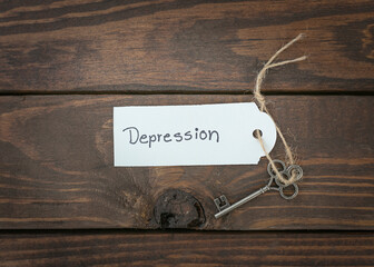 The key of depression concept isolate. Silver key with a label on wood table.