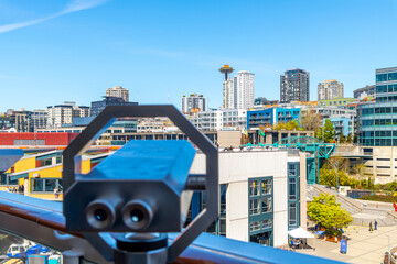 A tower viewing telescope binoculars is blurred in the foreground as the skyline of Seattle,...