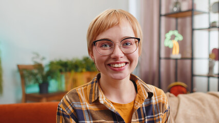 Close-up portrait of happy calm young woman at home couch smiling friendly, glad expression looking...