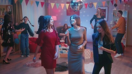 At the party, teenagers dance in separate groups. A group of three girls are dancing separately, the girls are talking, smiling. Dance of three girlfriends close up. Party, birthday, celebration.