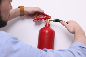 Man checking quality of fire extinguisher indoors, closeup