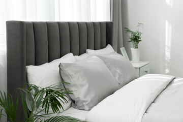 Stylish bedroom interior with comfortable bed and beautiful houseplants