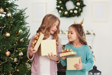 Cute little girls opening Christmas gifts at home