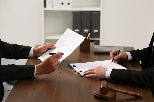 Law and justice. Lawyers working with documents at wooden table in office, closeup