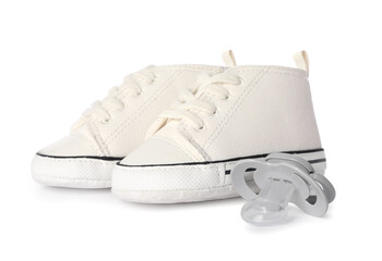 Sneakers and baby pacifier isolated on white