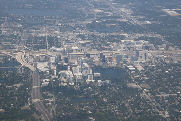 A bustling cityscape surrounded by lush greenery, Orlando, Florida aerial view showcases theme...