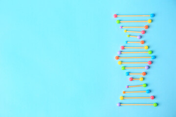 DNA molecule model made of toothpick and colorful beads on light blue background, flat lay. Space...
