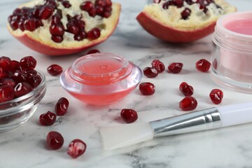 Homemade cosmetic product and fresh pomegranate on white marble table. DIY beauty recipe