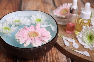 Spa composition. Bowl with water and beautiful flowers on wooden table, closeup. Space for text