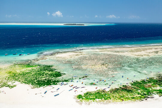 Boats on idyllic sand beach with Mnemba Island in the background, Zanzibar, Tanzania