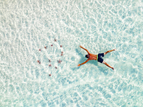 Aerial view of tourist admiring the colorful starfish snorkeling in the turquoise lagoon, Zanzibar, Tanzania