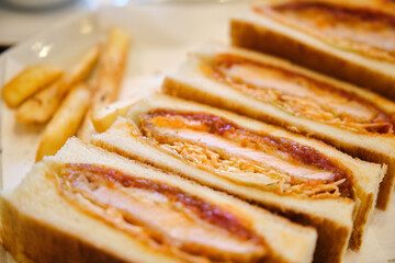 Katsu sando japanese sandwich with breaded pork chop, cabbage and tonkatsu sauce in a cafeteria.