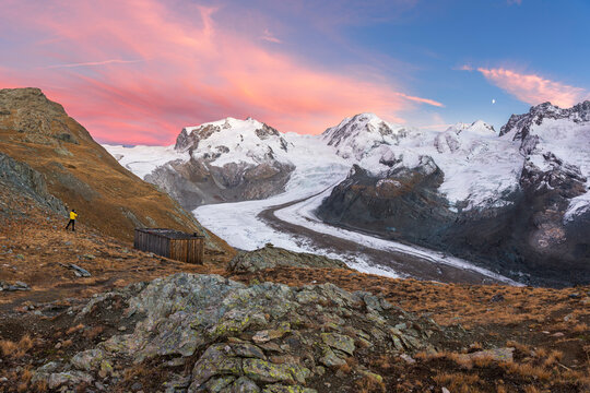 Hiker admiring snow covered peaks of Monte Rosa massif and the Gorner Glacier (Gornergletscher), Gornergrat, Zermatt, Valais Canton, Swiss Alps, Switzerland