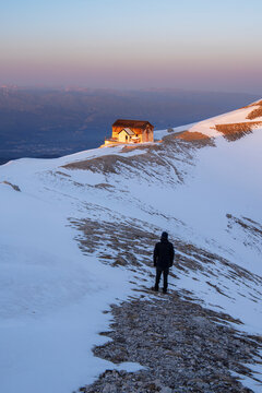 Winter view of a hiker admiring the sunset at Duca degli Abruzzi mountain hut, Campo Imperatore, Apennines, L'Aquila district, Abruzzo, Italy