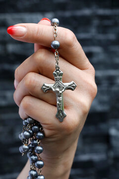 Woman praying with a silver crucifix and a rosary with beads, Concept for Christian religion, faith and prayer, Vietnam