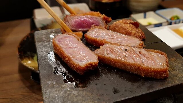 chopsticks grill gyukatsu on hot pan Japanese food beef loin fried and let people cook their own beef level rare to well done